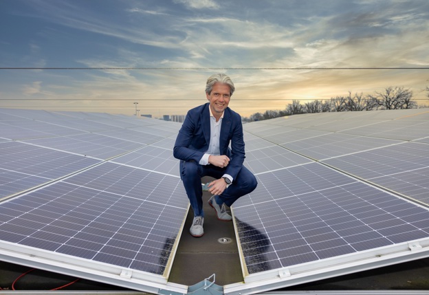 Wim ter Steege gehurkt tussen twee rijen zonnepanelen op het dak van zijn bedrijf.