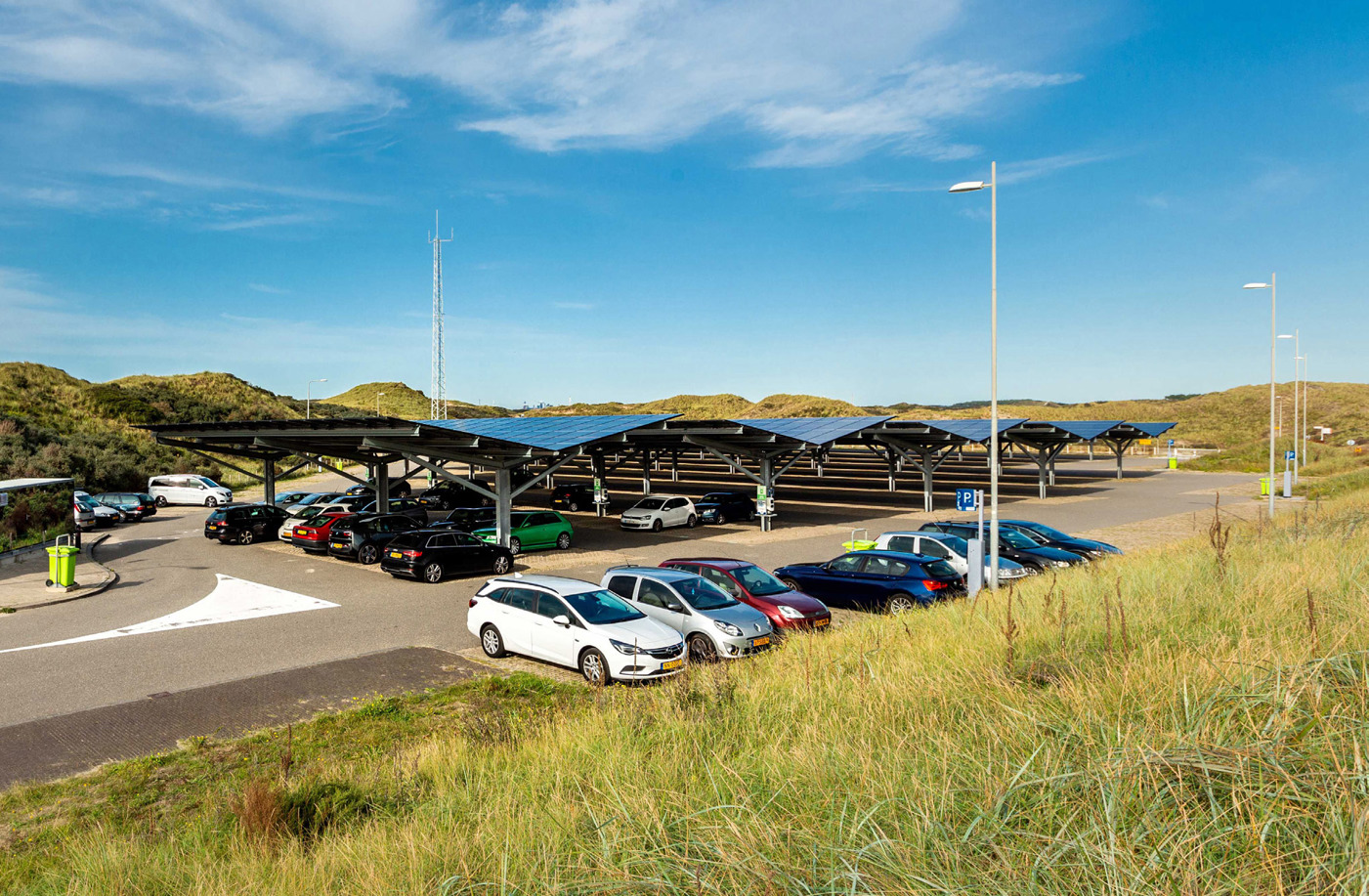 Zonnecarpoort: parkeerplaats met auto's met een overkapping van zonnepanelen op een zonnige dag.