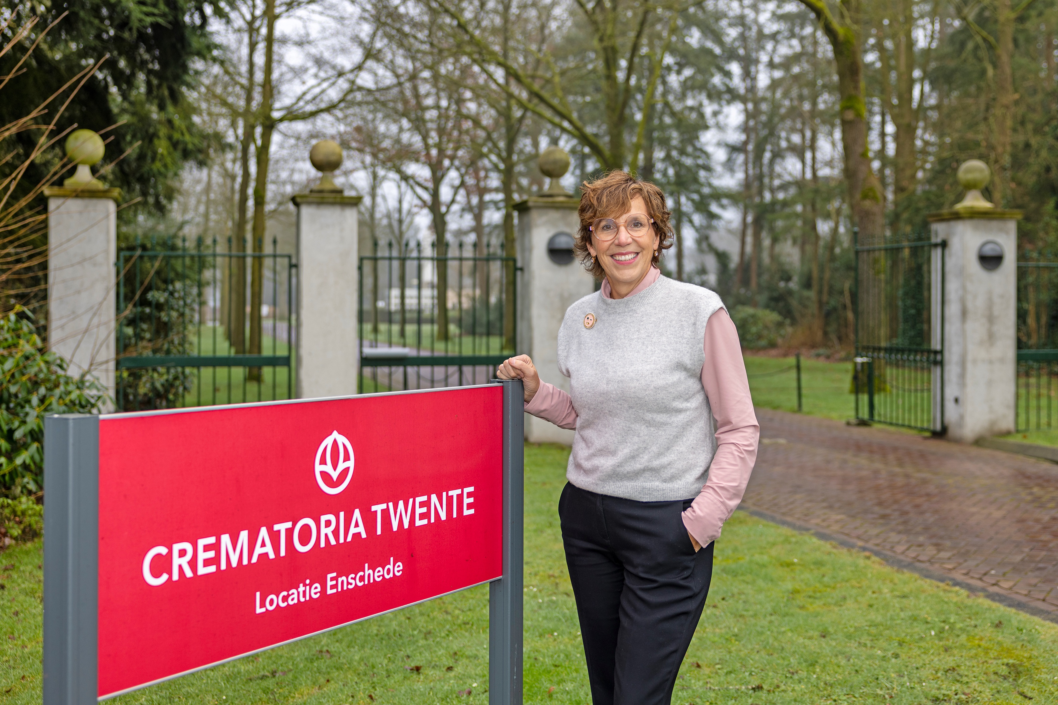 Harriet Tomassen, directeur-bestuurder van Crematoria Twente, buiten bij een bord van de crematoria, locatie Enschede.