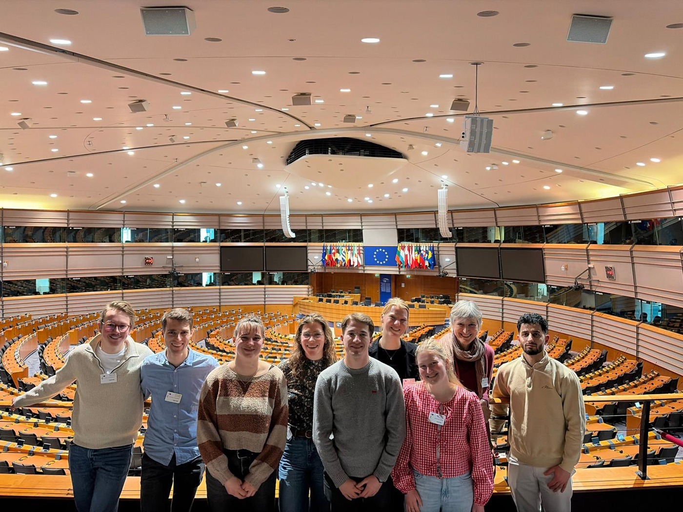 Groep van negen trainees hop de tribune hoog op de tribune van een verder lege Statenzaal van de provincie Overijssel.